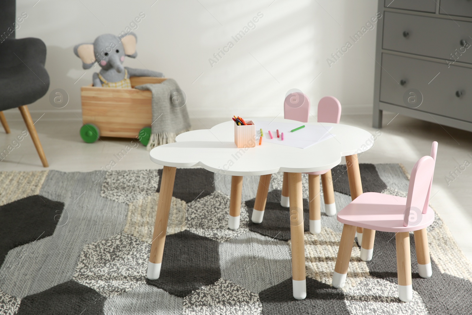 Photo of Little table and chairs with bunny ears in children's room. Interior design