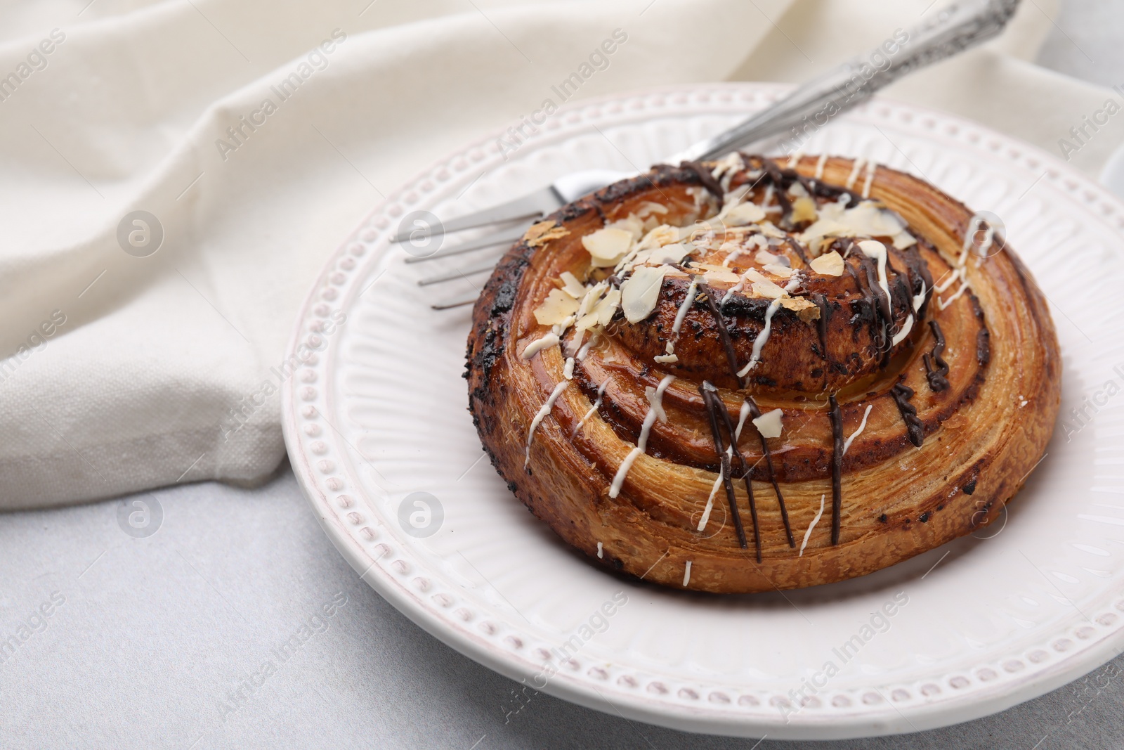 Photo of Delicious roll with poppy seeds, topping and fork on light table, closeup with space for text. Sweet bun