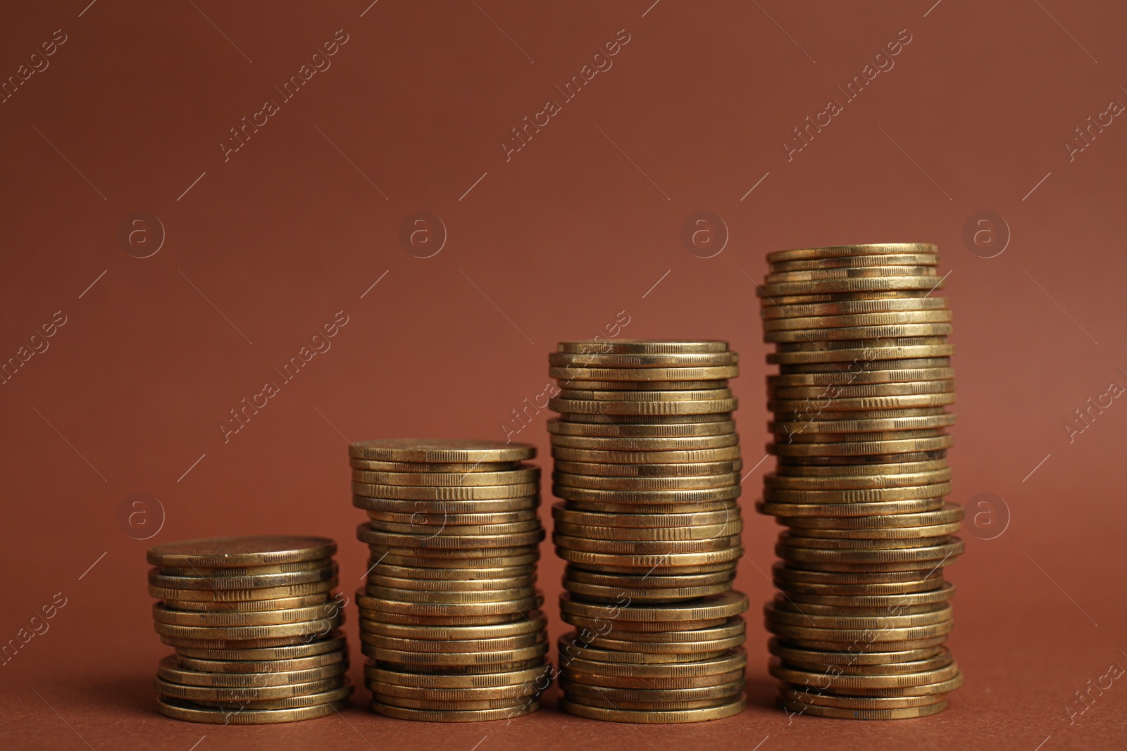 Photo of Many golden coins stacked on brown background, space for text