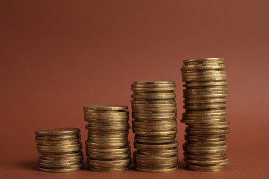 Photo of Many golden coins stacked on brown background, space for text
