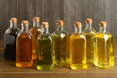 Photo of Vegetable fats. Different oils in glass bottles on wooden table
