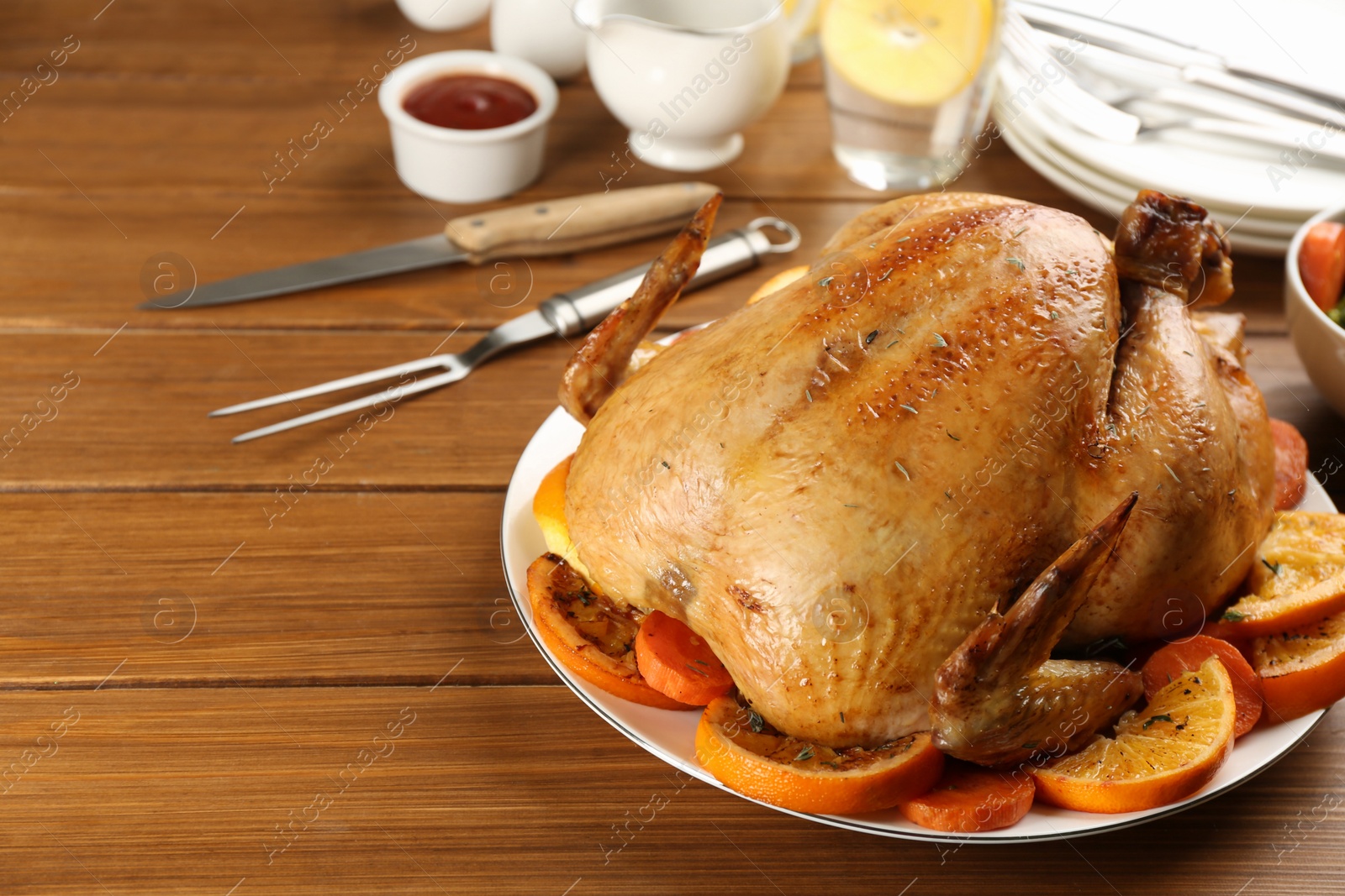 Photo of Delicious chicken with oranges on wooden table