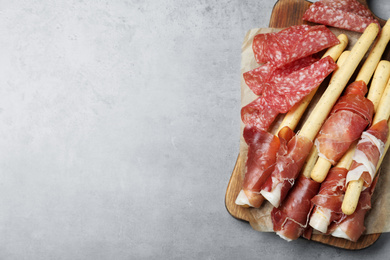 Tasty prosciutto and salami on light grey table, top view. Space for text