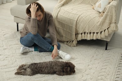 Photo of Sad young woman and her dog sitting on floor at home