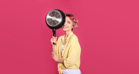 Photo of Young housewife with frying pan on pink background