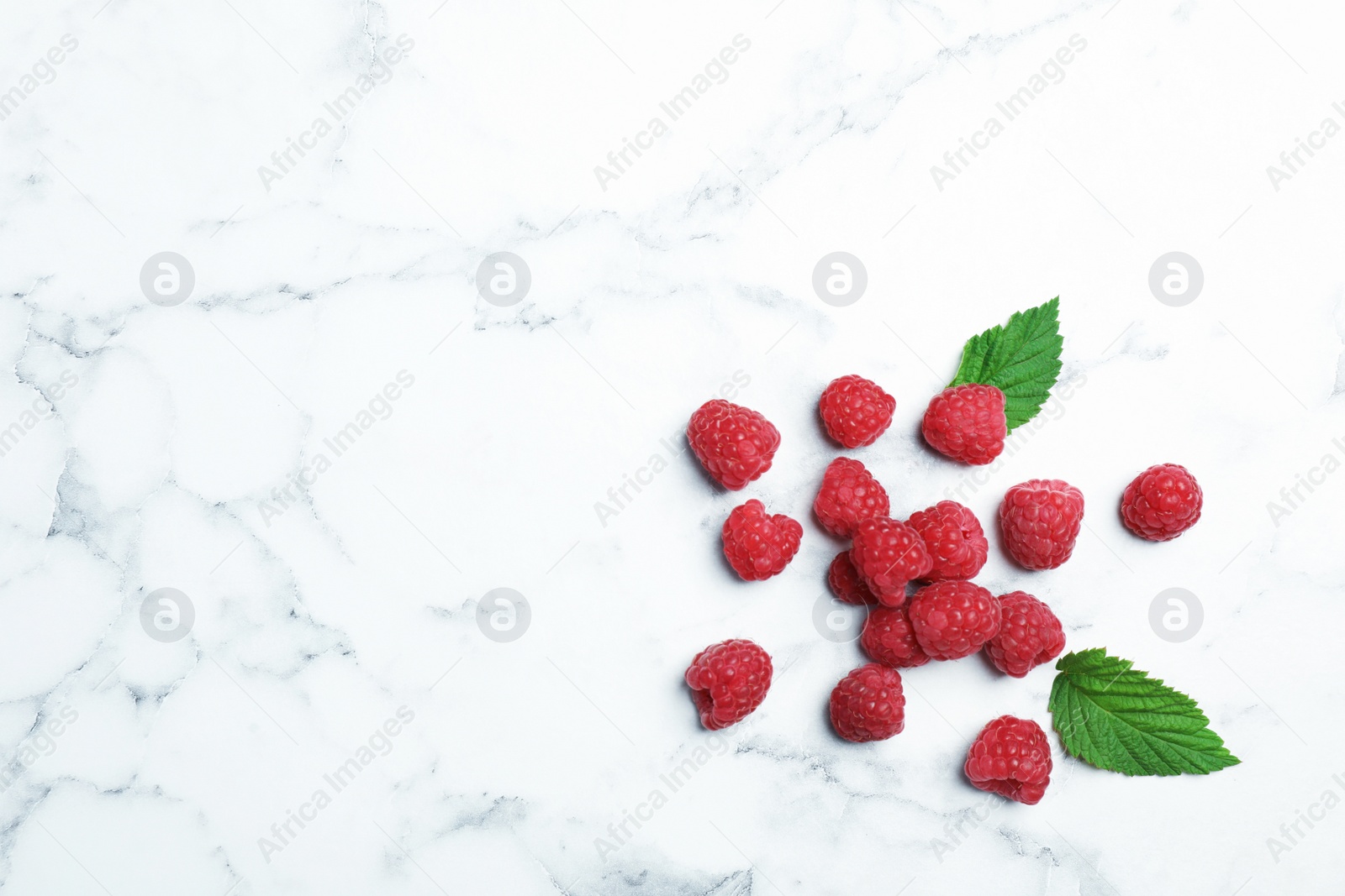 Photo of Ripe aromatic raspberries on marble table, top view