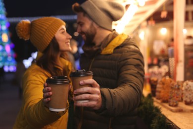 Photo of Lovely couple spending time together at Christmas fair, focus on hands with cups