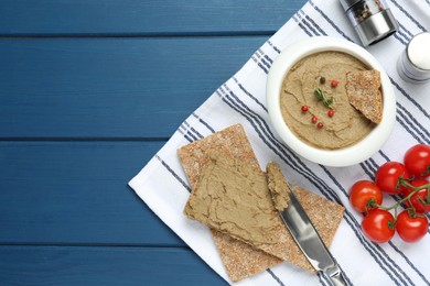 Photo of Tasty liver pate, crispy crackers and tomatoes on blue wooden table, flat lay. Space for text