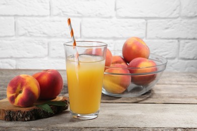 Photo of Glass of delicious peach juice with ice and fresh fruits on wooden table