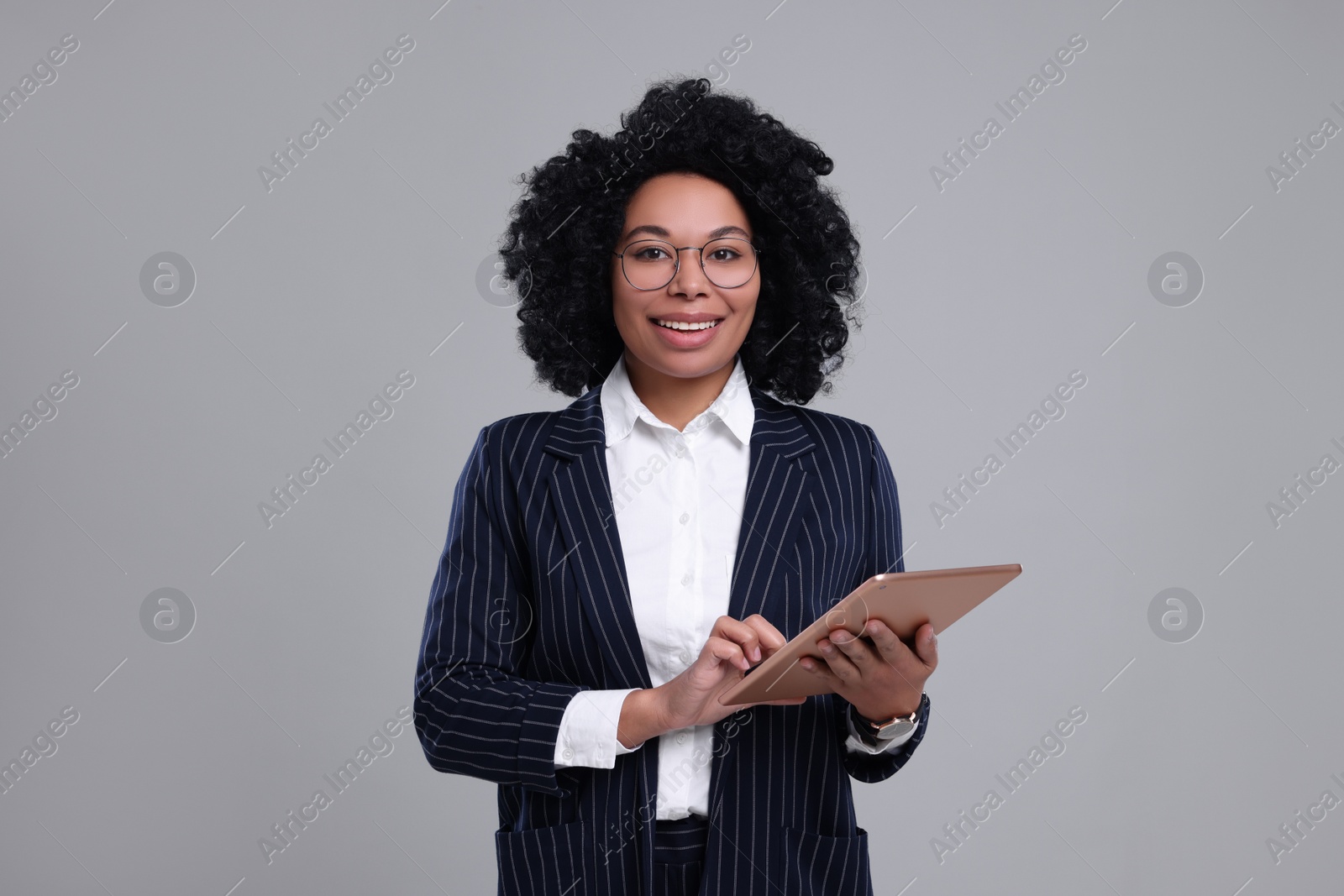 Photo of Young businesswoman with tablet on grey background