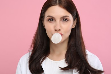 Photo of Beautiful woman blowing bubble gum on pink background