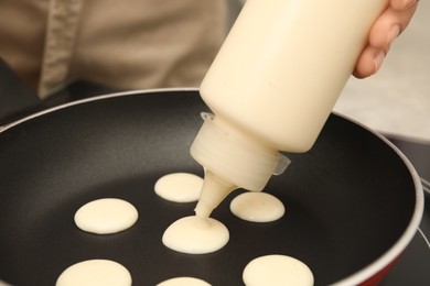 Photo of Woman cooking cereal pancake on frying pan, closeup