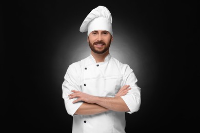 Photo of Smiling mature male chef on black background