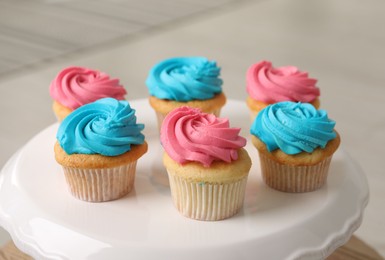 Photo of Delicious cupcakes with bright cream on dessert stand indoors, closeup