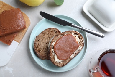 Photo of Tasty sandwich with quince paste served for breakfast on light grey marble table, flat lay