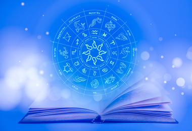 Image of Open book and illustration of zodiac wheel with astrological signs on blue background