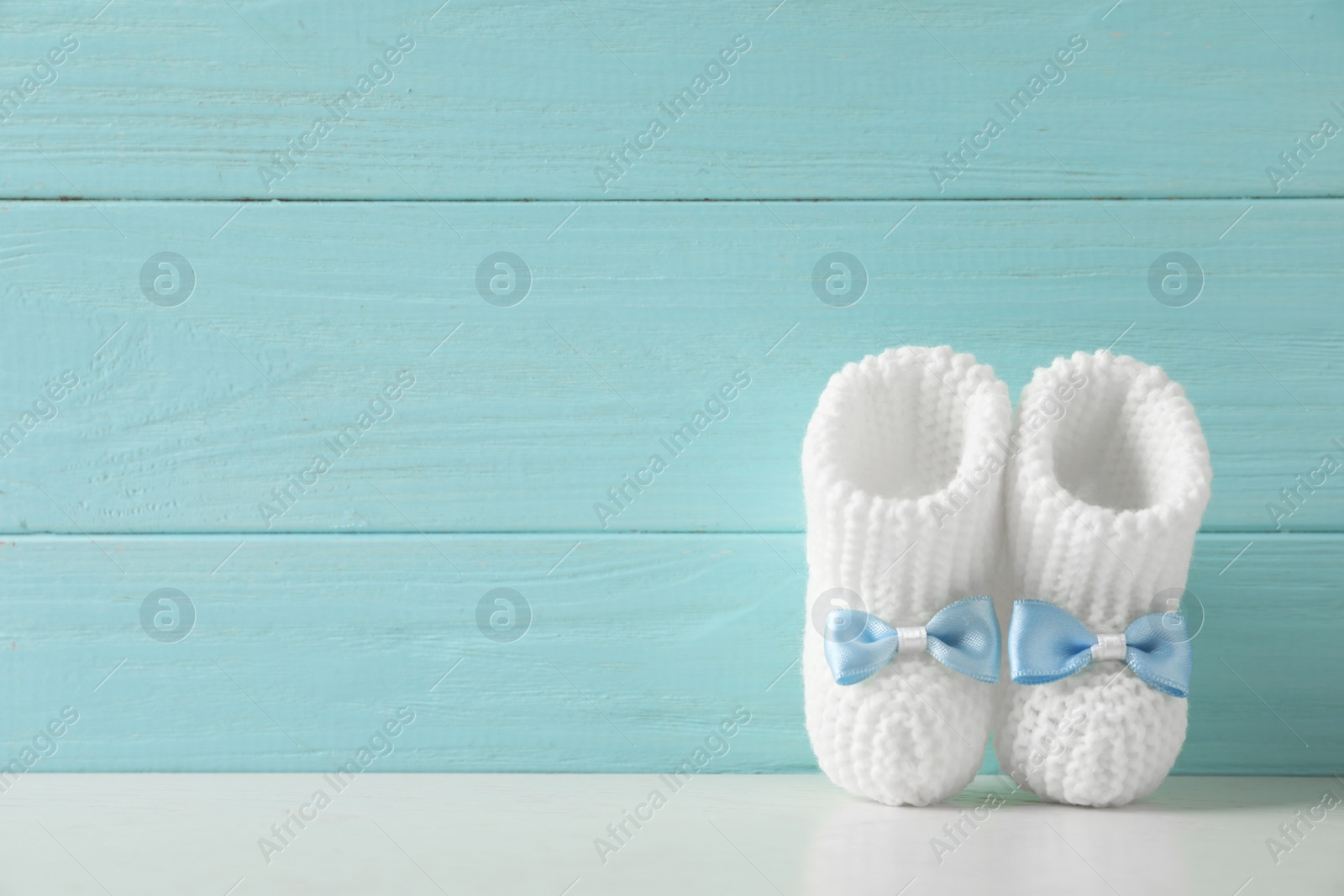 Photo of Handmade baby booties on table against wooden background. Space for text