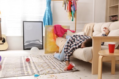 Young man sleeping on sofa in messy room after party