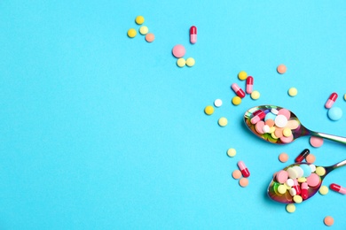 Spoons and different pills on color background