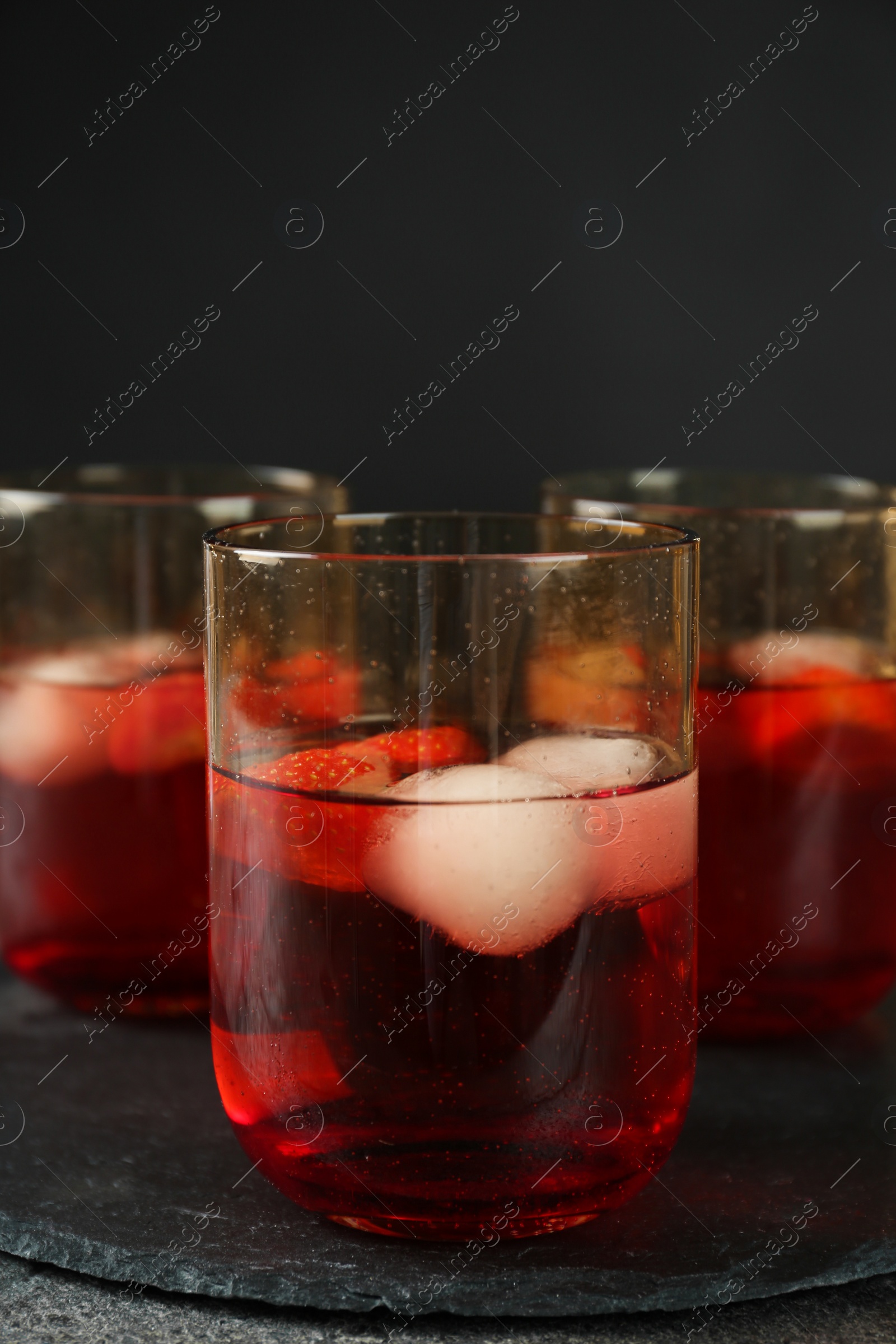 Photo of Delicious cocktails with strawberries and ice balls on grey table