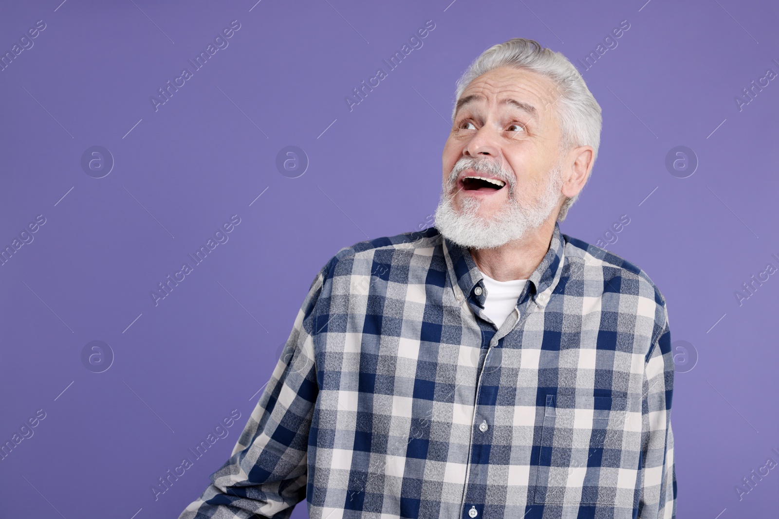 Photo of Portrait of surprised senior man on violet background, space for text