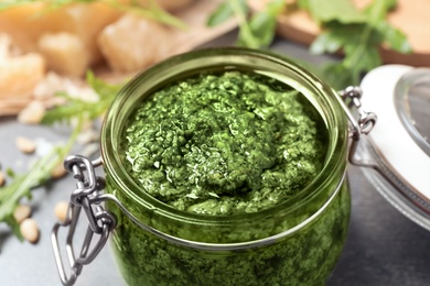 Jar of tasty arugula pesto on table, closeup