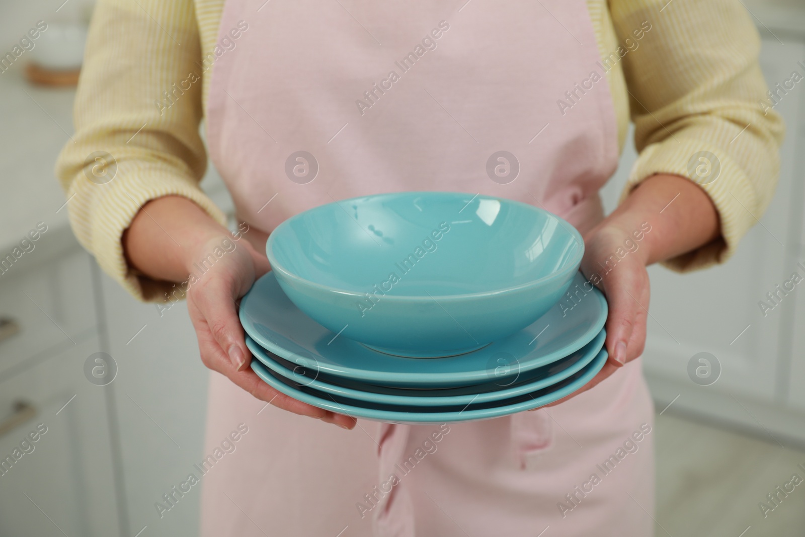 Photo of Woman holding plates in kitchen, closeup view