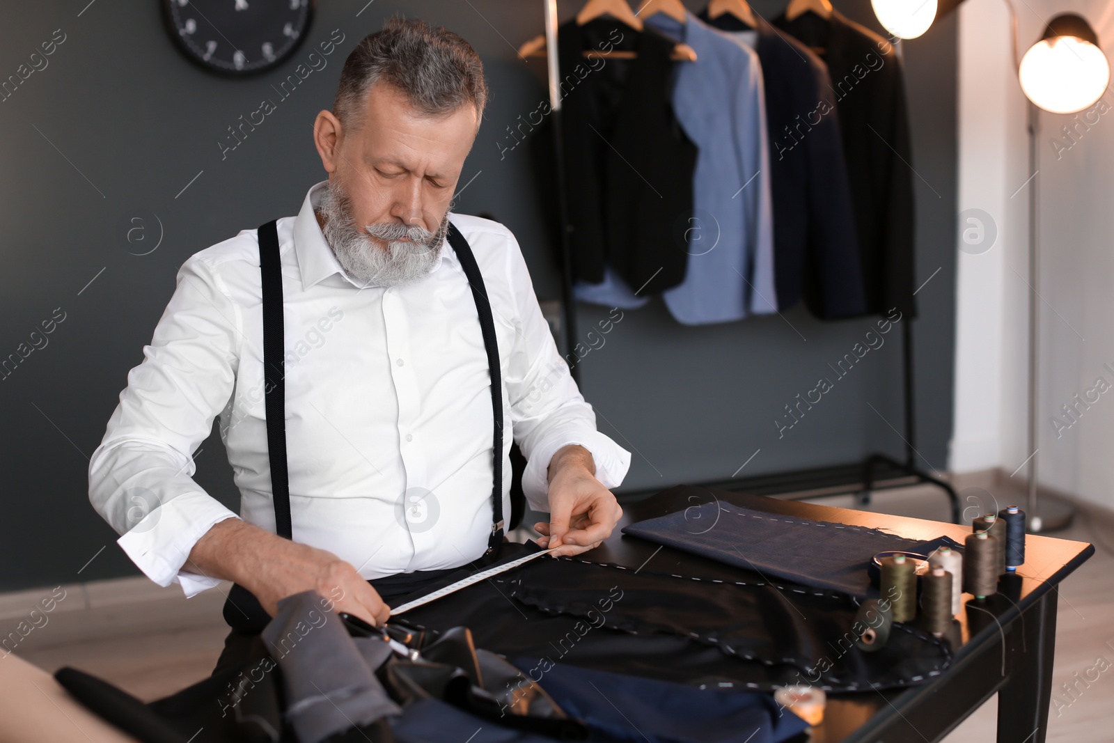 Photo of Mature tailor working with sewing pattern in atelier