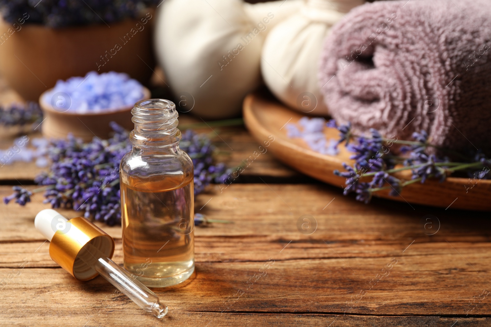 Photo of Composition with essential oil and lavender flowers on wooden table. Space for text