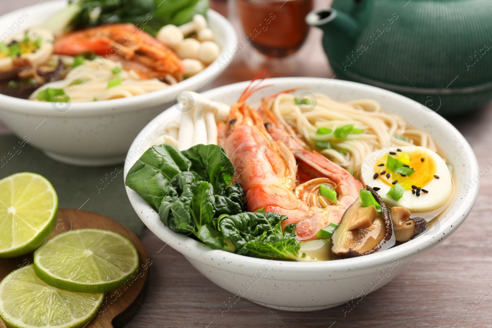 Photo of Delicious ramen with shrimps and egg in bowl on wooden table, closeup. Noodle soup