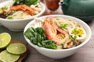 Delicious ramen with shrimps and egg in bowl on wooden table, closeup. Noodle soup