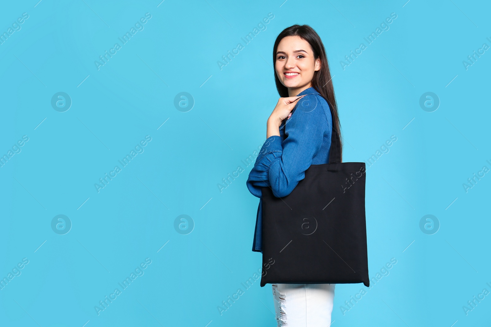 Photo of Beautiful young woman with stylish blank eco bag against color background, space for text