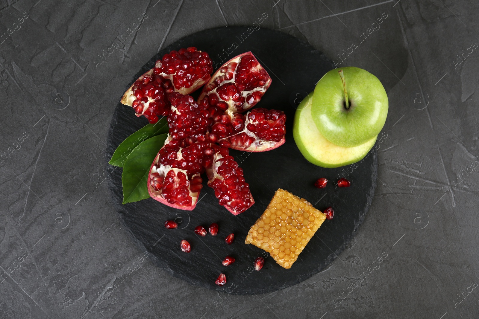 Photo of Composition with honeycomb, apples and pomegranate on grey table, top view. Rosh Hashanah holiday