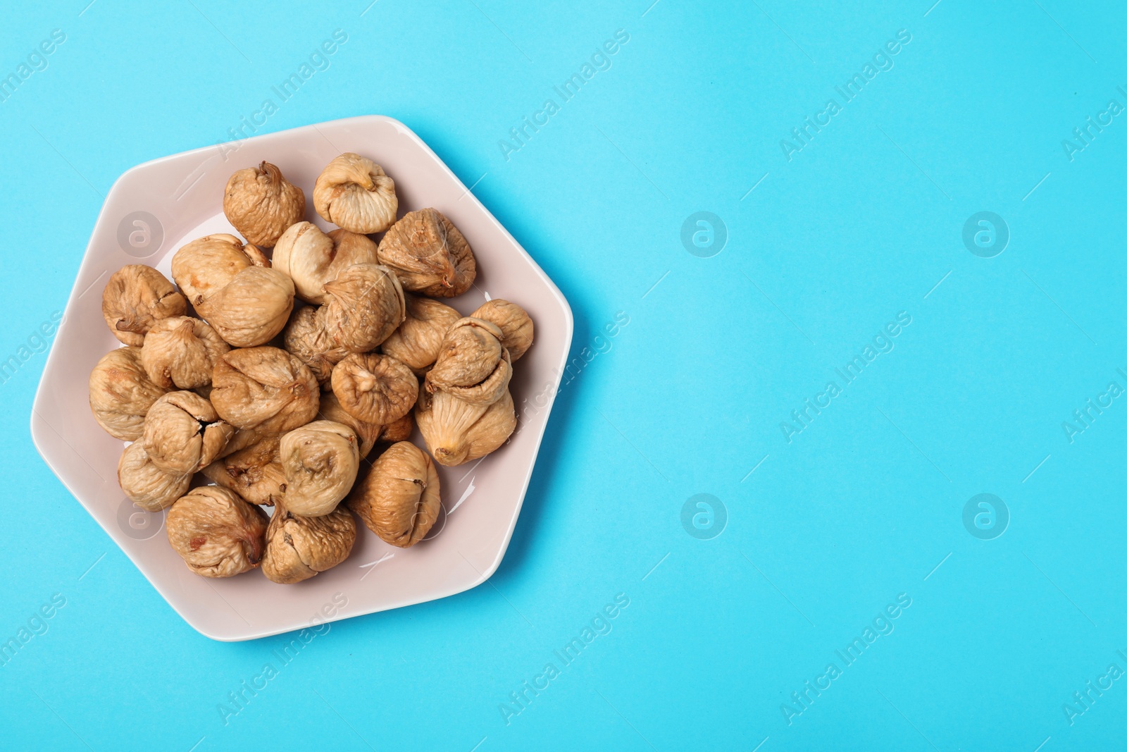 Photo of Plate of dried figs on color background, top view with space for text. Healthy fruit