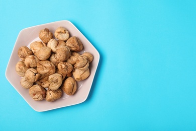 Photo of Plate of dried figs on color background, top view with space for text. Healthy fruit