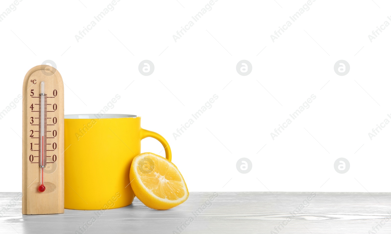 Photo of Thermometer, lemon and cup of hot tea on wooden table against white background. Space for text