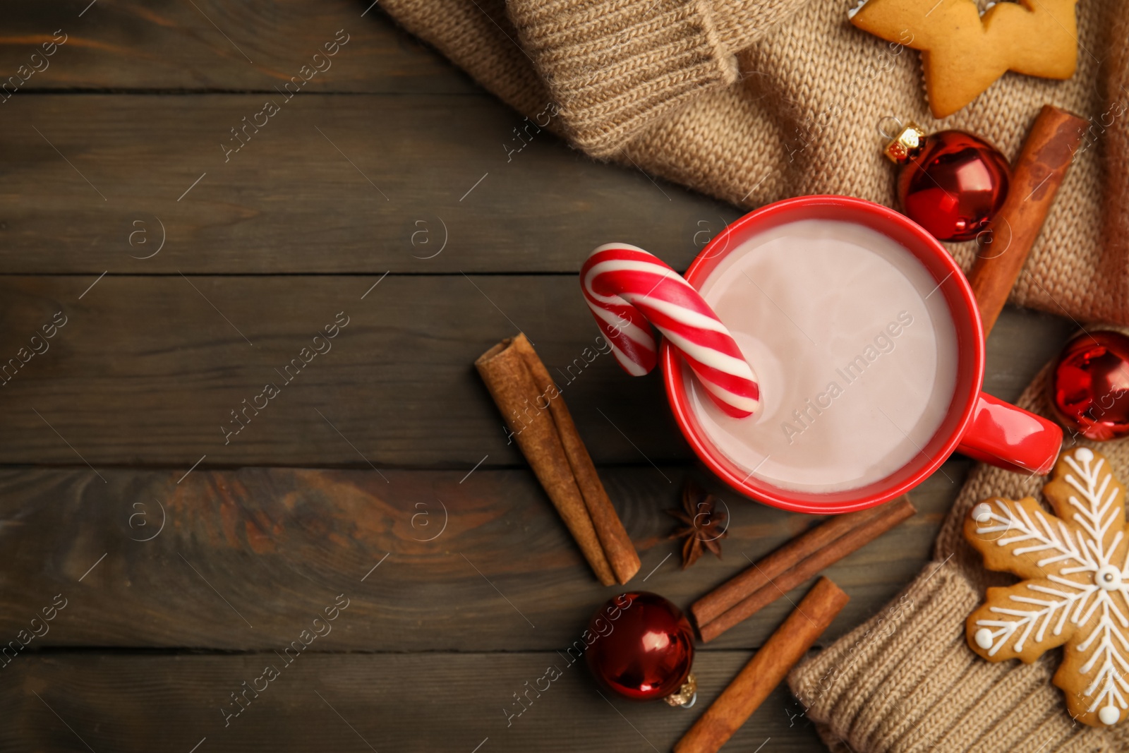 Photo of Flat lay composition with cup of tasty cocoa and Christmas candy cane on wooden table, flat lay. Space for text