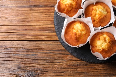 Delicious sweet muffins on wooden table, top view. Space for text