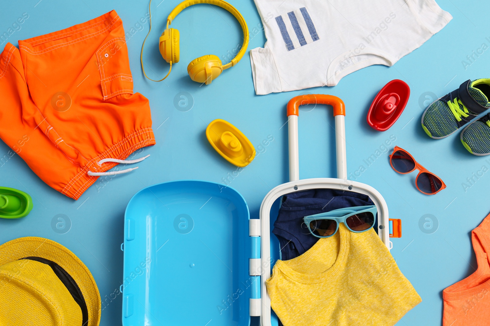 Photo of Flat lay composition with child suitcase and accessories on blue background