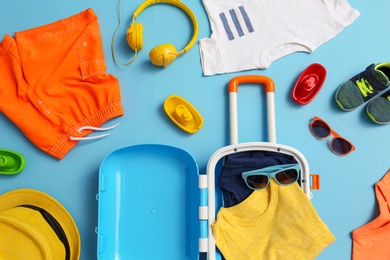 Flat lay composition with child suitcase and accessories on blue background