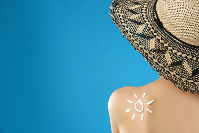 Photo of Woman with sun protection cream on her back against light blue background. Space for text