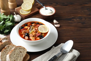 Photo of Meat solyanka soup with sausages, olives and vegetables served on wooden table, space for text