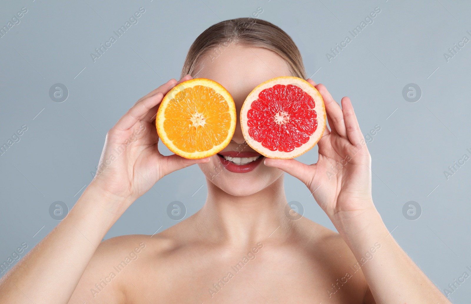 Photo of Young woman with cut orange and grapefruit on grey background. Vitamin rich food