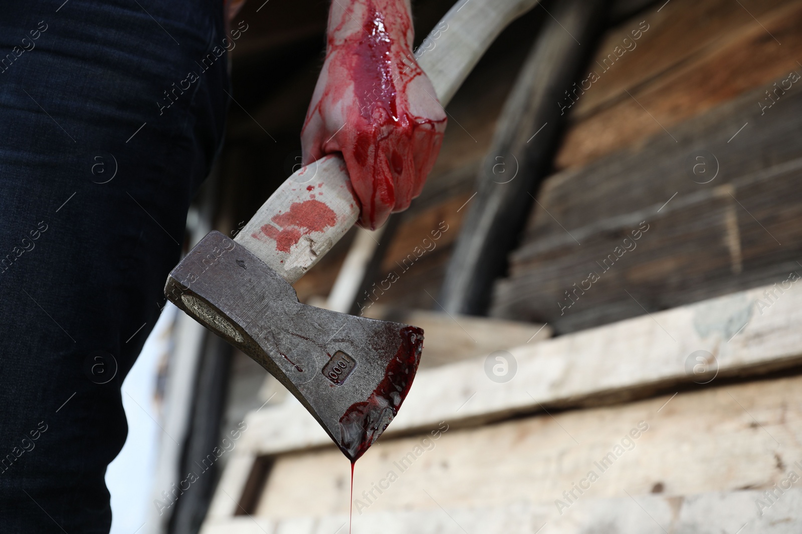 Photo of Man holding bloody axe outdoors, closeup. Space for text