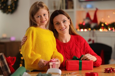 Photo of Christmas presents wrapping. Mother and her little daughter with gift boxes at table in room
