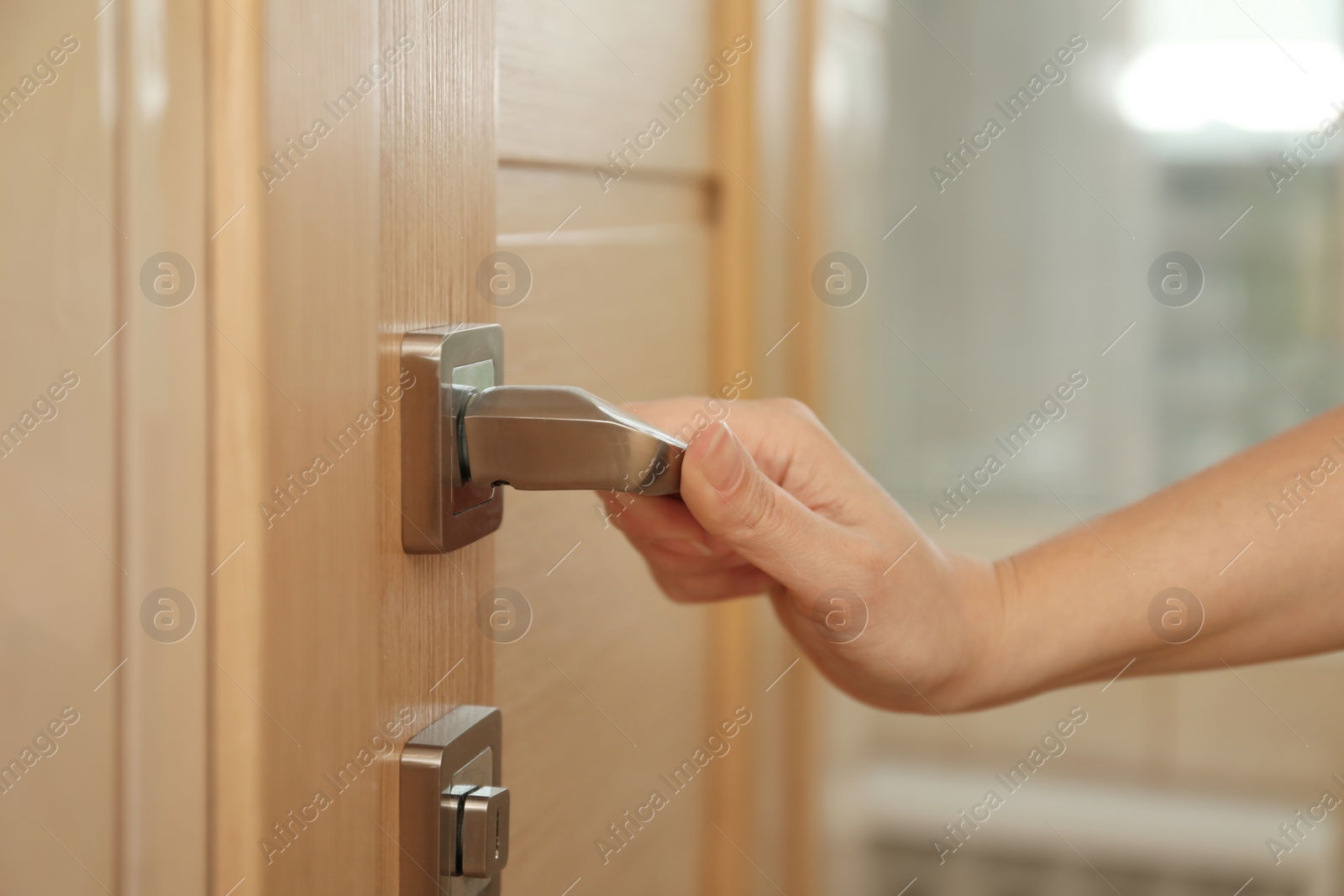 Photo of Woman opening door indoors, closeup of hand