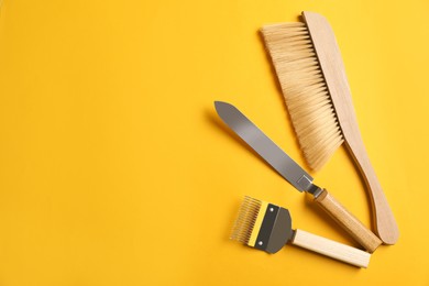 Photo of Beekeeping tools on yellow background, flat lay. Space for text