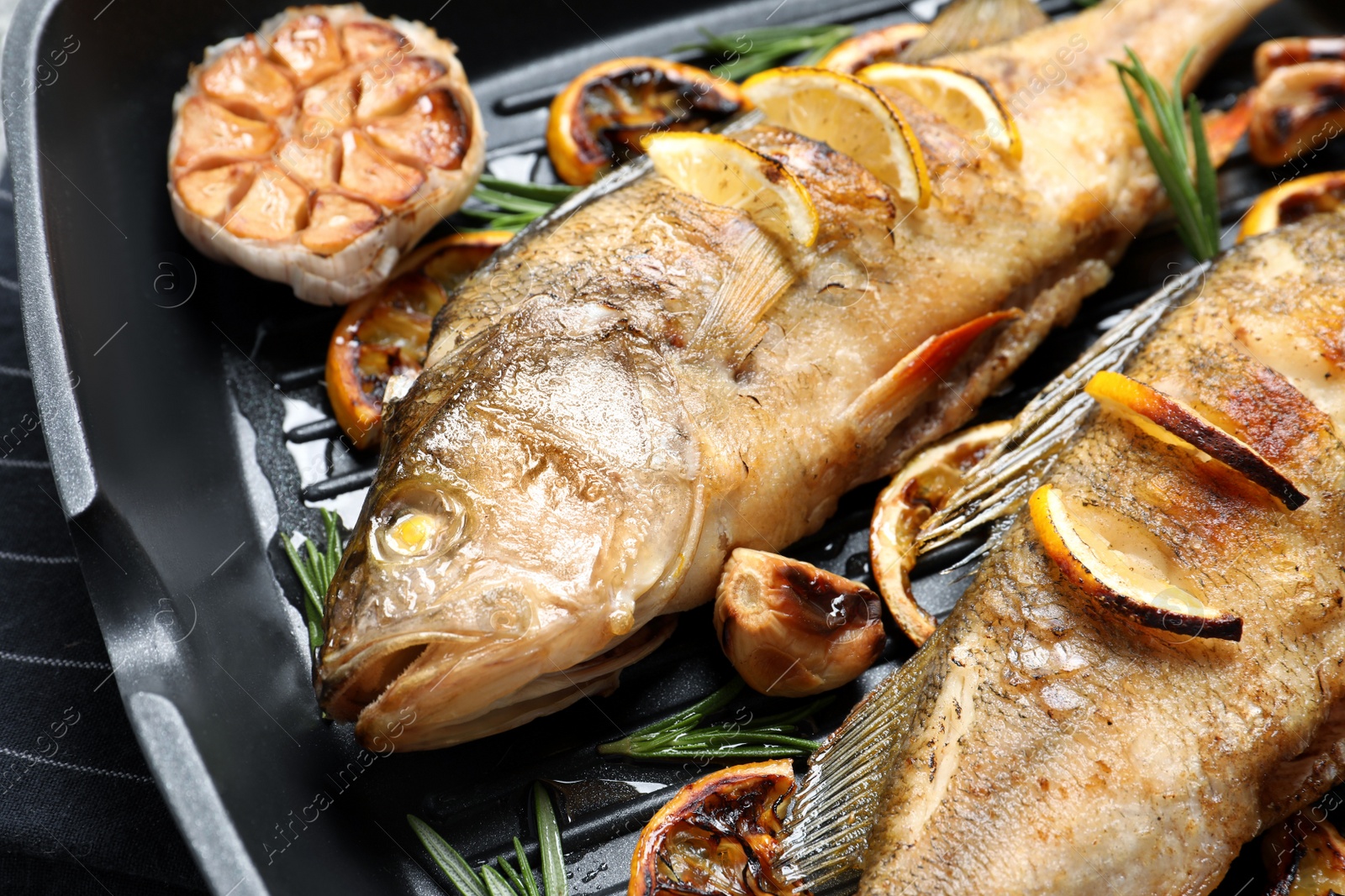 Photo of Tasty homemade roasted perches in grill pan, closeup. River fish