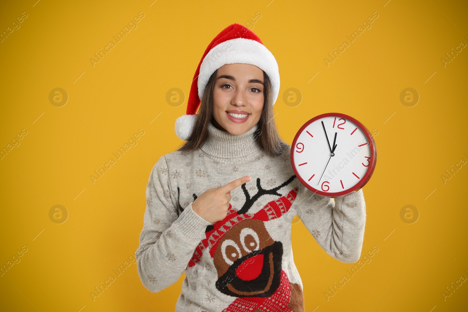 Photo of Woman in Santa hat with clock on yellow background. New Year countdown