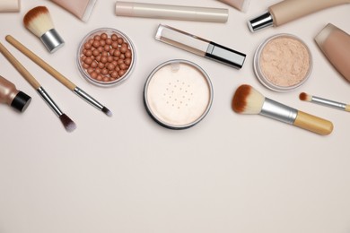 Face powders and other makeup products on beige background, flat lay. Space for text